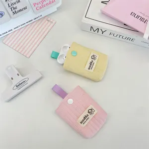 Close-up detail showing pastel yellow and pink quilted earphone storage pouches