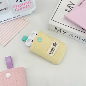 Close-up of a cream yellow quilted AirPods storage pouch with a mint green snap button