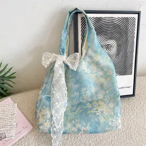 Detailed macro view of the blue floral tote bag featuring an elegant white lace bow charm