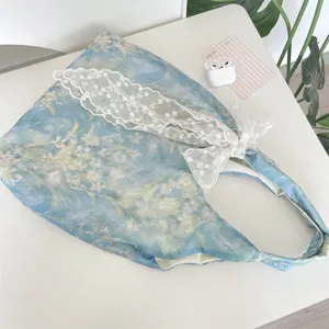 Close-up of blue impressionist floral tote bag with elegant white lace bow detail