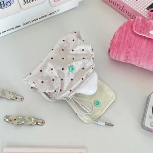 Gedetailleerd zicht op een roze satijnen zakje met stippen en drukknop voor kabels