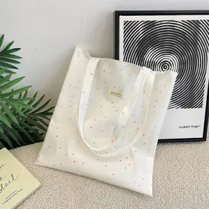 Gedetailleerd overzicht van een witte canvas draagtas met kleurrijke stippen in een literaire setting