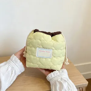 Vista detallada de la bolsa con cordón acolchada de corazón en suave tela amarillo crema