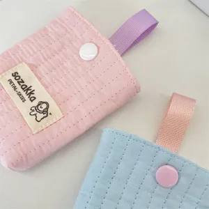 Detailed texture of quilted earphone storage pouch with contrast ribbon and snap button