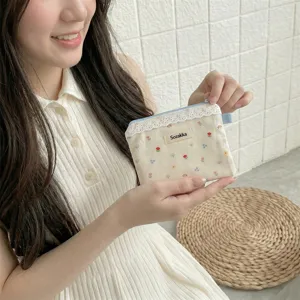 Vue détaillée d'une pochette fleurie en toile avec dentelle délicate tenue par une femme.