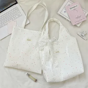 Detailweergave van witte canvas tassen met polkadots en elegante kanten strikjes