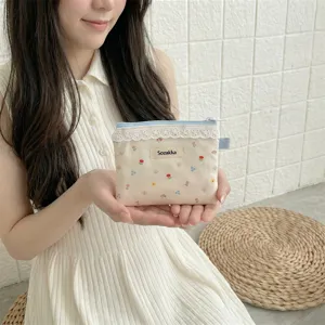 Mannequin tenant une petite pochette en toile à fleurs avec bordure en dentelle