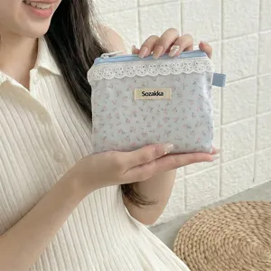 Vue détaillée d'une pochette de rangement fleurie bleu clair avec dentelle et fermeture éclair.