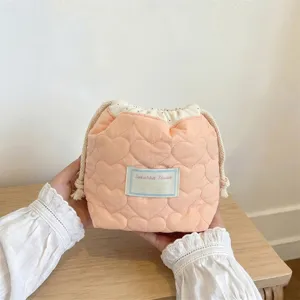 Detalle de primer plano del patrón acolchado de corazones en un neceser rosa con cordón ajustable