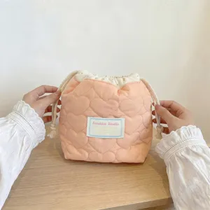 Vista detallada de una bolsa de cosméticos rosa acolchada con corazones y cordón en las manos