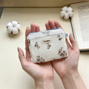 Gros plan d'une petite pochette de rangement à fleurs avec dentelle tenue dans les mains