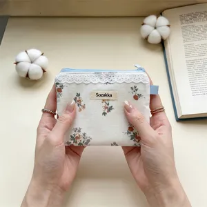 Détail d'une pochette en coton à fleurs avec bordure en dentelle et étiquette Sozakka