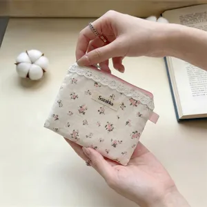 Détail de la petite pochette en toile fleurie avec bordure en dentelle et fermeture éclair.
