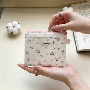 Gros plan d'une pochette à fleurs avec bordure en dentelle blanche et fermeture éclair rose