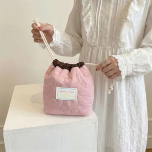 Vista detallada de una bolsa de cosméticos rosa acolchada con corazones y cordón ajustable