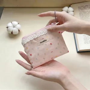 Détail d'une pochette à fleurs roses avec bordure en dentelle blanche et étiquette Sozakka