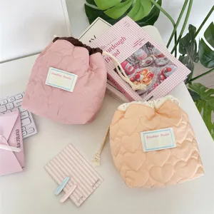 Detalle de dos bolsas con cordón acolchadas con corazones en un escritorio blanco