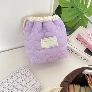 Primer plano de una bolsa con cordón acolchada de corazones morados en un escritorio blanco
