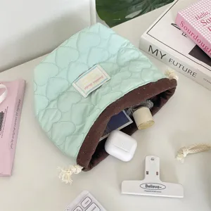 Primer plano del bolso acolchado de corazón con cordón en verde menta y marrón.