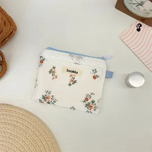 Gros plan d'une petite pochette en toile fleurie avec bordure en dentelle et zip bleu