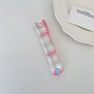 Dettaglio dell'organizzatore per cavi a quadri macaron con bottone a pressione a cuore rosa
