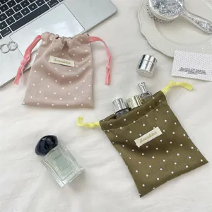 Detailed macro view of pink and olive green polka dot satin drawstring storage bags.