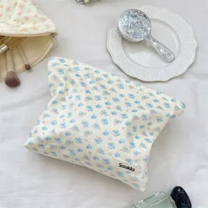 Close-up view of the cream corduroy cosmetic bag with delicate blue floral patterns.