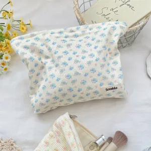 Detail view of cream floral corduroy makeup bag featuring delicate blue flowers