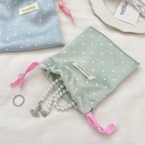 Detailed view of a pastel satin polka dot drawstring bag for jewelry storage and travel
