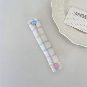 Dettaglio dell'organizzatore per cavi in tessuto a quadretti macaron con bottone a cuore