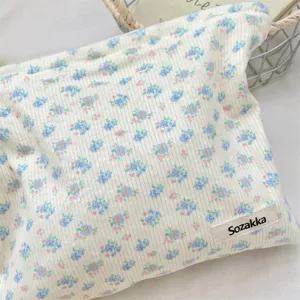 Detailed close-up of white corduroy makeup bag featuring delicate blue floral prints.