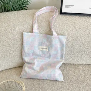 Macro view of pastel pink and blue patchwork checkered canvas tote bag on sofa