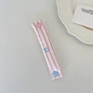 Dettaglio dell'organizer per cavi a righe rosa con grazioso bottone a pressione a cuore