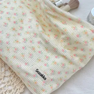 Detailed close-up of a cream corduroy floral makeup bag with soft velvet texture