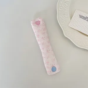 Dettaglio del ferma cavi rosa floreale con bottone a cuore su un piatto decorativo.