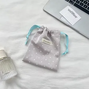 Close-up of a satin polka dot drawstring pouch for jewelry storage on white fabric