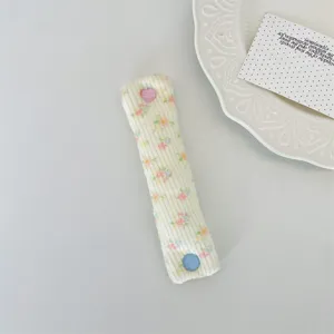 Dettaglio dell'organizzatore cavi in maglia floreale con bottone a cuore