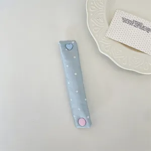Primo piano di fascetta in tessuto azzurro a pois con un simpatico bottone a cuore