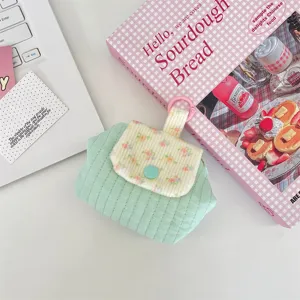 Detail of a mint green floral quilted coin purse with a contrast blue snap button.