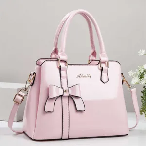 Detailed view of pink patent leather handbag featuring elegant bow and gold logo