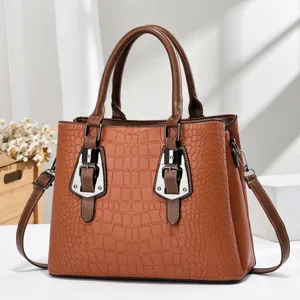 Detail view of the elegant brown crocodile embossed handbag with metal buckle accents.