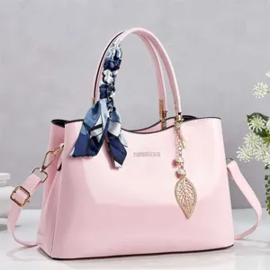 Elegant pink patent leather handbag with decorative silk scarf and gold leaf charm.
