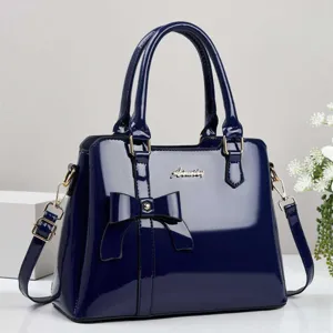 Elegant navy blue patent leather handbag with a stylish bow detail and gold-tone hardware