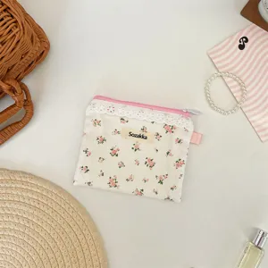 Vue détaillée d'une pochette fleurie avec bordure en dentelle et fermeture rose