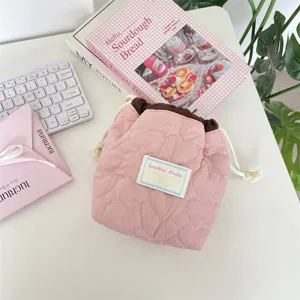 Neceser rosa acolchado con corazones junto a libros y teclado en un escritorio blanco