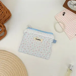 Gros plan d'une petite pochette fleurie bleu clair avec bordure en dentelle blanche.