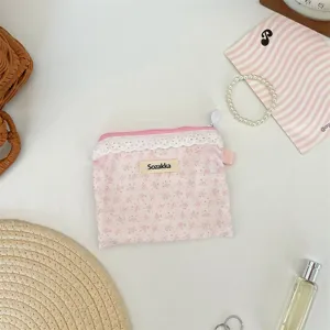 Gros plan d'une pochette fleurie rose avec bordure en dentelle blanche et fermeture éclair