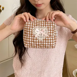 Close up of quilted brown plaid makeup bag with cute lace heart and pink bow detail.