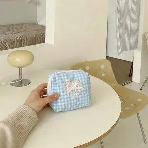 Close up view of the blue and white plaid quilted cosmetic bag featuring delicate lace heart and bow.
