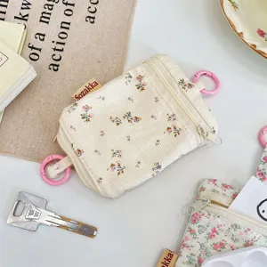Floral corduroy coin pouch with double zippers and pink clips for keys, detailed view.